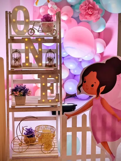 A decorative ladder shelf spelling 'ONE' with light-up letters, surrounded by fairy-themed props.