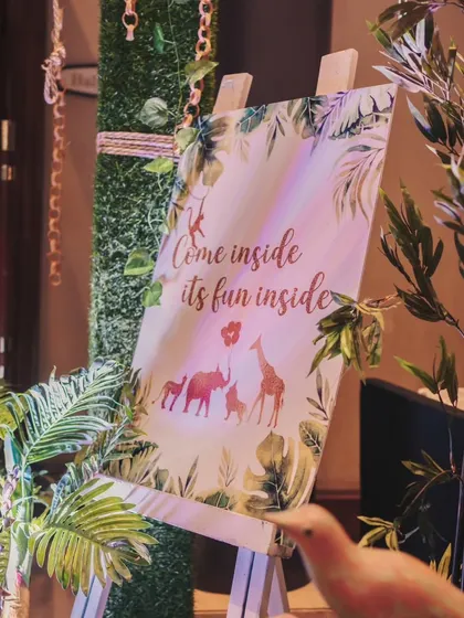 "Come inside, it's fun inside!" This charming welcome sign on an easel, surrounded by lush greenery, invited guests into Ved's jungle adventure.