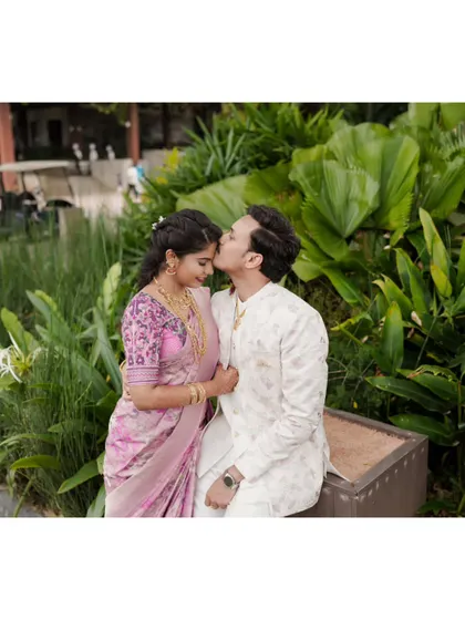 A tender forehead kiss, capturing the romance of an engagement shoot in a lush garden setting.