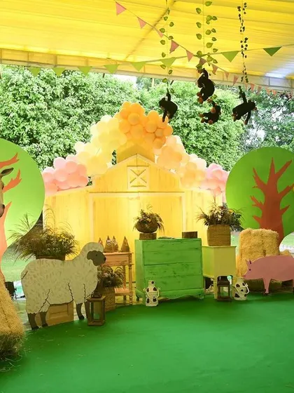The main backdrop for the Boho animal party was a charming barnyard scene, with cutouts of a horse, sheep, and pig, set against a soft yellow barn facade.