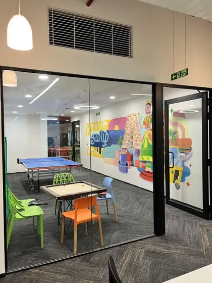 A full view of the Kissflow game room, designed with modular furniture and glass walls. This allows for transparency and connection with the rest of the office while containing the noise and activity of the recreational space.
