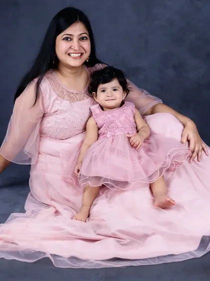 A mother and daughter in matching pink dresses sit together for a beautiful portrait. A perfect way to capture the special bond they share.