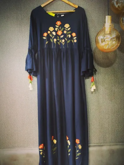 A contemporary take on the classic long dress in a deep navy blue. This piece features beautiful floral embroidery on the yoke and hem, with tassel details on the sleeves for a playful touch.