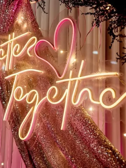 A "Better Together" neon sign adds a modern and romantic touch to any wedding backdrop. Here, it's set against a shimmering sequin fabric, creating a glamorous photo opportunity.
