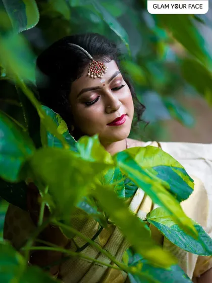 A closer look at this beautiful Onam celebration makeover. The focus is on the eyes, with a soft shimmer and a bold lip, perfectly framed by a floral messy bun and traditional maang tikka.