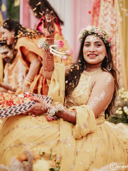 A happy bride shows off her henna-adorned hands during the Haldi ceremony, surrounded by family.