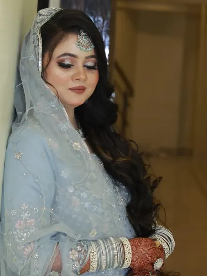 A beautiful portrait of a bride in a powder blue outfit. The makeup is soft and glowing.