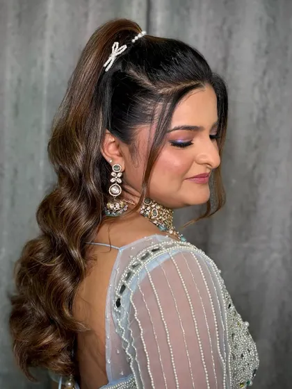 A chic and modern look for a 'Bandoli' ceremony, featuring a high ponytail and a pastel blue outfit.