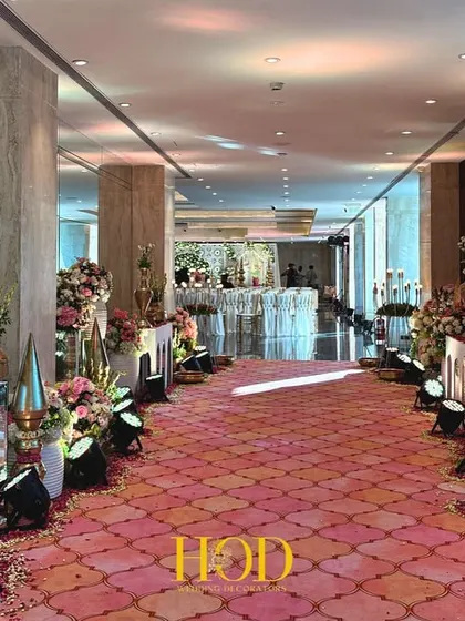 I designed this long, opulent aisle to build a sense of grandeur. Lined with arched decor elements, fresh flowers, and traditional brass vessels on a vibrant pink carpet, it creates a royal path leading to the main wedding ceremony.