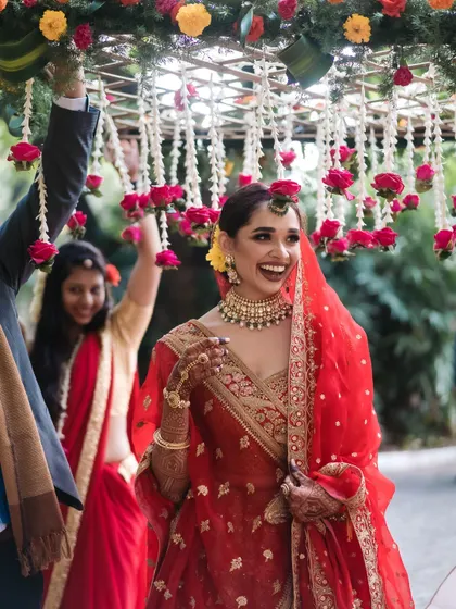 A joyous bride makes her entrance under a 'phoolon ki chadar' (floral canopy) that we designed with fresh roses and jasmine, adding a traditional and beautiful touch to her walk.