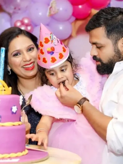 A sweet moment as a father helps his daughter, the birthday girl, take her first bite of cake.