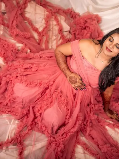 An artistic overhead shot where the textured pink gown creates a beautiful bed of ruffles for the mom-to-be.
