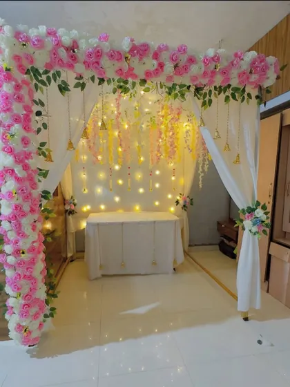 A beautiful and complete mandap setup for your home. The pink and white floral arch is complemented by soft drapes and delicate hanging details.