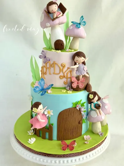 I designed this two-tiered cake as a whimsical fairy and mushroom village. It’s filled with tiny, handmade fairies, edible butterflies, and cute mushroom houses, creating an enchanting scene for a first birthday.