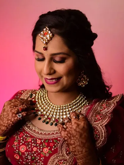 A model styled for a reception or sangeet in a red lehenga, wearing a beautiful Kundan necklace and maang tikka.