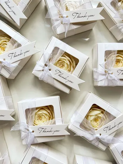 White peony candles in window boxes with "Thank you" tags. This is a classic and elegant packaging option for wedding favors.