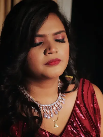 A dramatic and moody shot of a reception look, highlighting the shimmering red eyeshadow and diamond necklace.