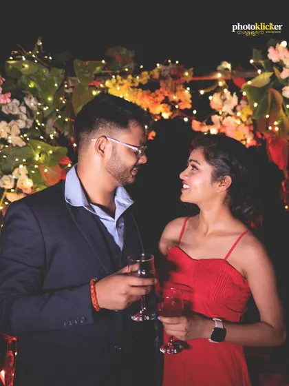 A close-up shot of a couple sharing a drink at a romantic, candlelit dinner setup on a river beach at night.