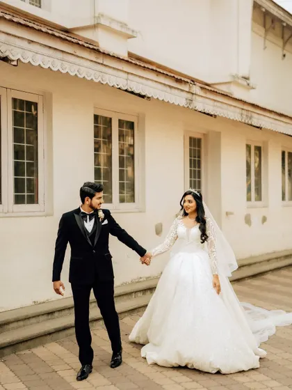 A happy, walking shot of the couple holding hands. This captures the movement and joy of the day against a clean, architectural background.