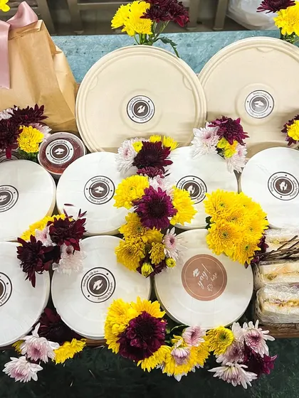 A beautifully assembled gift tray, featuring a variety of our meal bowls and sandwiches, decorated with fresh flowers. It's the perfect gift for a loved one.