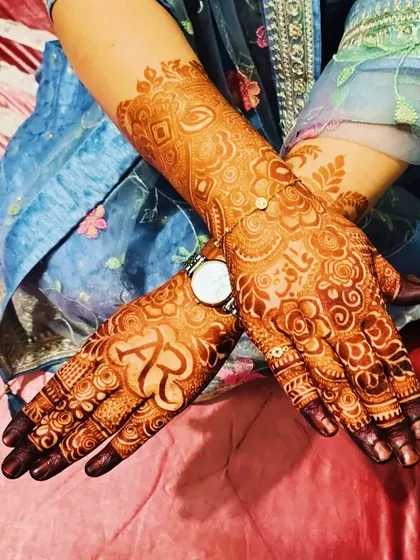 A candid shot showing the beautiful dark stain of a personalized bridal mehndi, complete with the couple's initials.