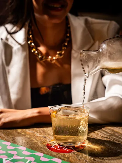 A lifestyle moment at Lyla Bombay, capturing a drink being poured at the table. This action shot makes the scene feel alive and engaging.