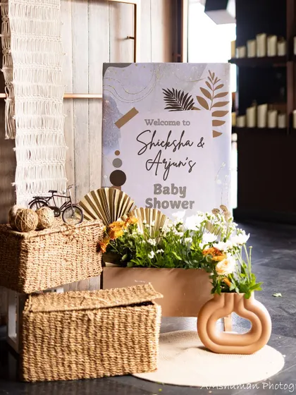 A stylish welcome sign for a boho-themed baby shower. The sign is placed next to rustic woven baskets and a modern vase, creating a chic and inviting entrance.