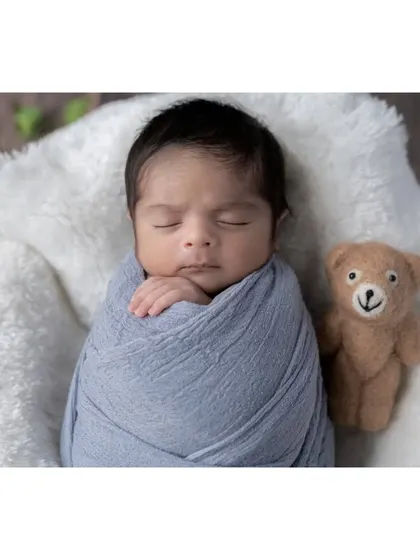 This little boy is sleeping so peacefully, swaddled in a soft blue wrap and accompanied by his teddy bear friend. I use simple, classic props that complement the baby without overwhelming the portrait.