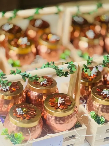 An array of corporate gift hampers featuring hammered copper jars in wooden crates, decorated with ivy vines.