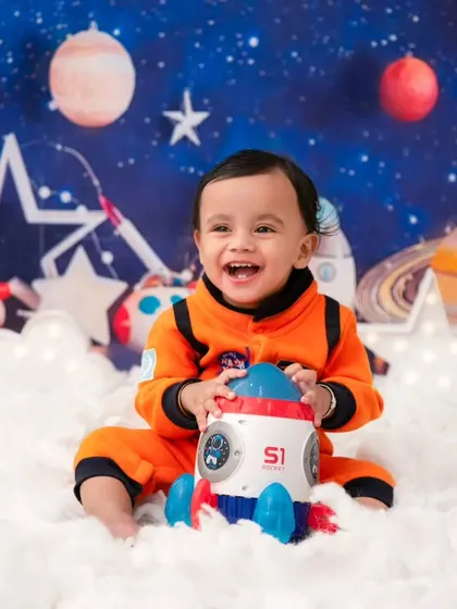 A happy little astronaut with his toy rocket. Themed props help engage children and bring out their most playful and genuine smiles.
