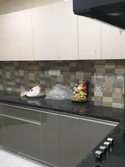 A delivered kitchen project with two-tone cabinets in glossy grey and white. The patterned tile backsplash adds a decorative element to this modern and functional cooking space.