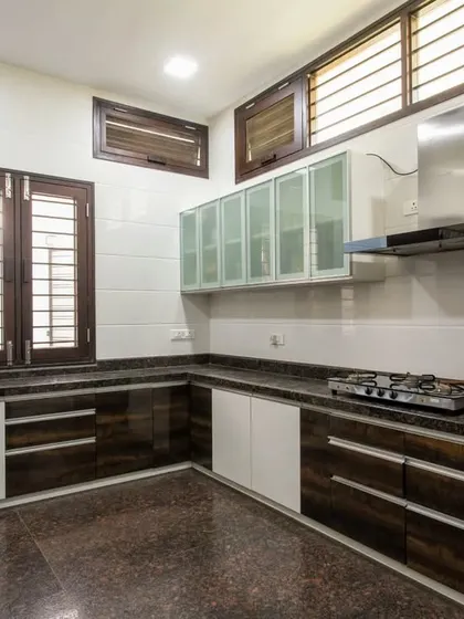 A modern and functional kitchen with a combination of wood-finish and white cabinets, a granite countertop, and ample ventilation from the louvered windows.
