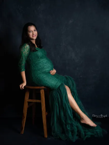 An elegant pose in an emerald green lace gown. The dark, moody backdrop helps to highlight the rich color of the dress and the beautiful silhouette of the mother-to-be.