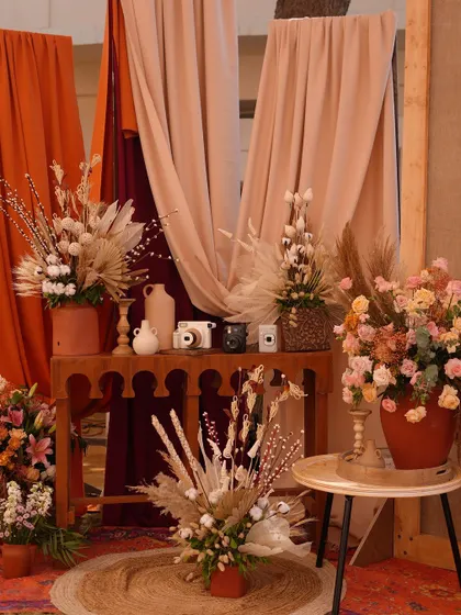 A bohemian-chic photo corner with rustic wooden furniture, dried flowers, and drapes in earthy tones of terracotta and beige.