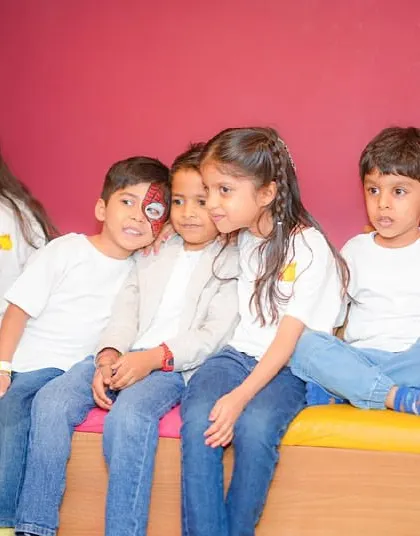 A group of kids in matching t-shirts sit together during a party.