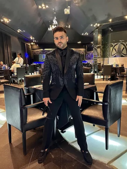 A client in an all-black look, featuring our tuxedo with vertical sequin stripes. This is a sleek, modern, and edgy choice for an evening event.