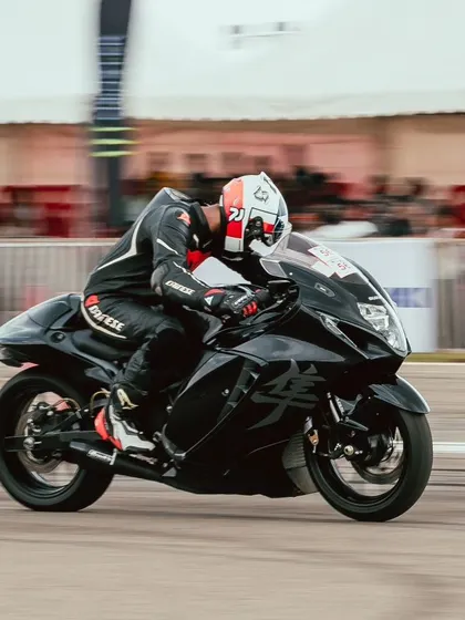 A rider on a black Suzuki Hayabusa, a legendary name in the world of speed, blasts down the drag strip.
