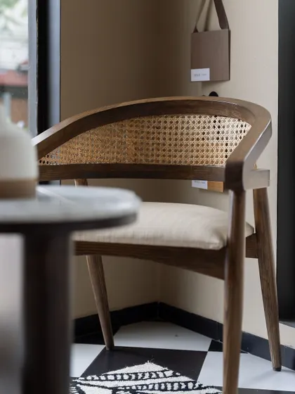 A classic armchair with a curved back and cane webbing, crafted from solid wood. This piece exemplifies our modern-vintage aesthetic, blending timeless materials with a contemporary form.