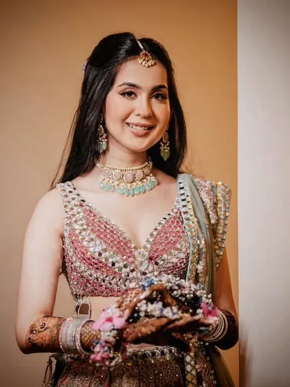 A portrait of the bride on her Mehendi day, looking fresh and radiant. Her look is completed with a mirror-work lehenga and delicate floral jewelry.