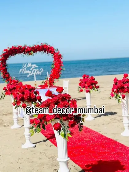 Another perspective of the beach proposal arrangement, focusing on the floral pedestals that line the aisle. These details add to the grandeur of the moment.