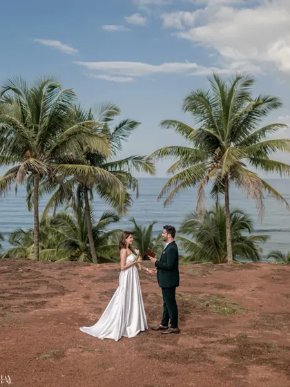 A wide shot showing the beautiful scale of a Goa proposal. The couple stands between towering palm trees with the ocean behind them, creating a picture perfect moment.