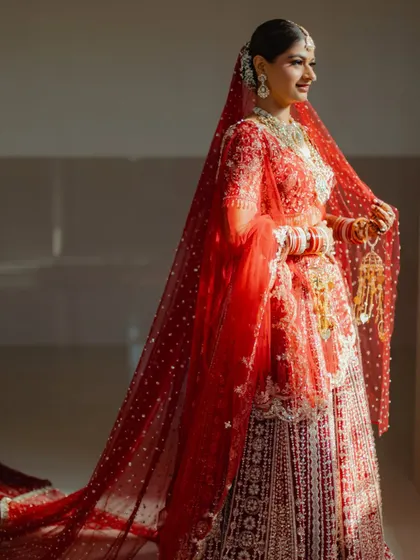 A beautiful shot of the bride getting her final touches. The sheer red dupatta adds a layer of tradition and mystique to her overall look.