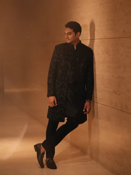 A stylish portrait of the groom, Mohnish. He wears a contemporary black sherwani by Shantanu & Nikhil, proving that groom styling can be modern and sharp.