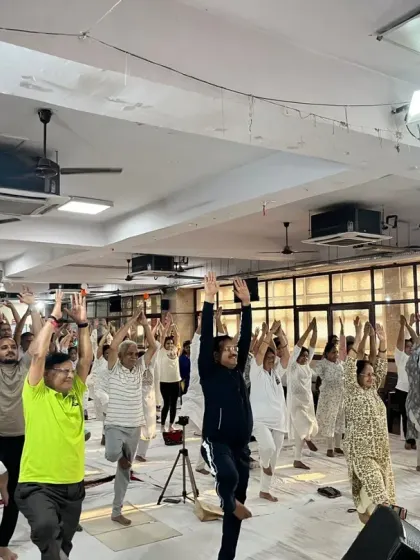 A large group of participants joyfully practicing Tree Pose (Vrikshasana) during our International Yoga Day event at Shree Balaji Mandir.
