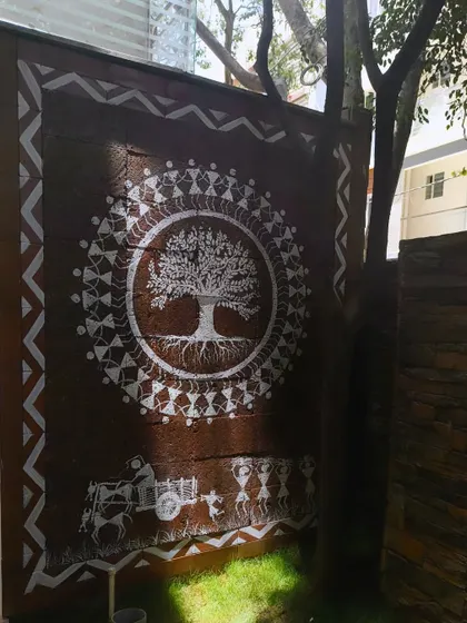A closer view of the Tree of Life mural. This angle shows the detail in the tree's roots and branches, as well as the ring of dancing figures that encircle it, a classic element of Warli tribal art.