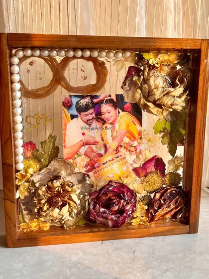 This teakwood frame is filled with a couple's wedding garland, with the threads shaped into an infinity symbol to represent their eternal love. It's a beautiful way to preserve the symbolism of your special day.