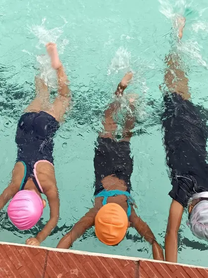 Kids practicing handstands in the water, a playful drill that helps with breath control and water comfort.