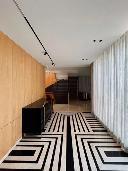 This hallway combines modern minimalism with a bold Art Deco influence. The striking black and white geometric flooring is contrasted by warm, light wood wall panels, creating a sophisticated and visually dynamic corridor.