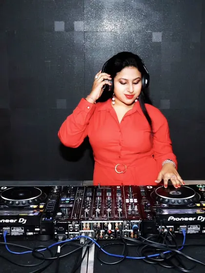 In a bright red shirt, focused on the Pioneer DJ mixer. The setup is my instrument, and I love exploring every feature to create the perfect sound.