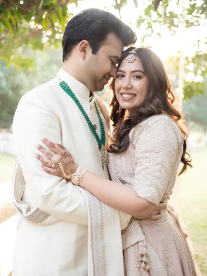 A warm, golden-hour portrait. The couple embraces, the bride smiling at the camera, her face full of joy and love.